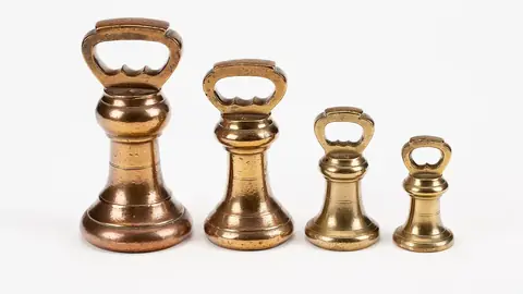 Four brass grocer's weights of decreasing size in a row