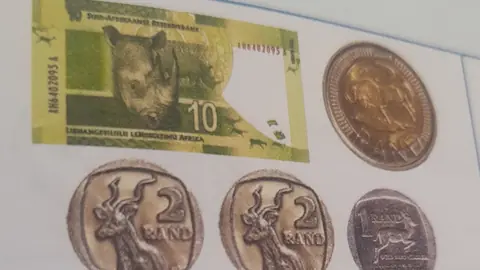 South African ten rand note with two and five rand coins