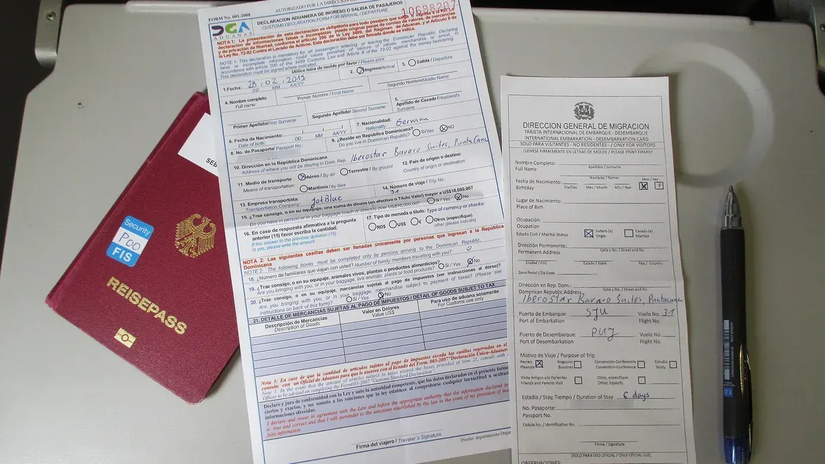 Passport, filled-in forms and a pen laid out on a tray table
