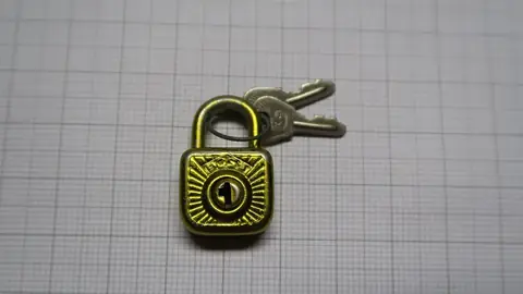 Small brass padlock with its keys on squared paper