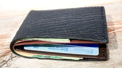 Leather wallet holding several cards on a weathered wooden table