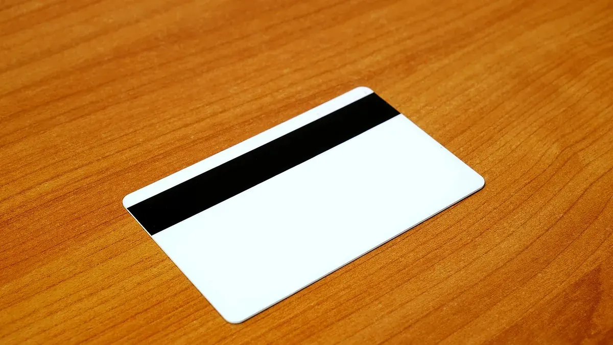 Plain white payment card with a magnetic stripe on a wooden table