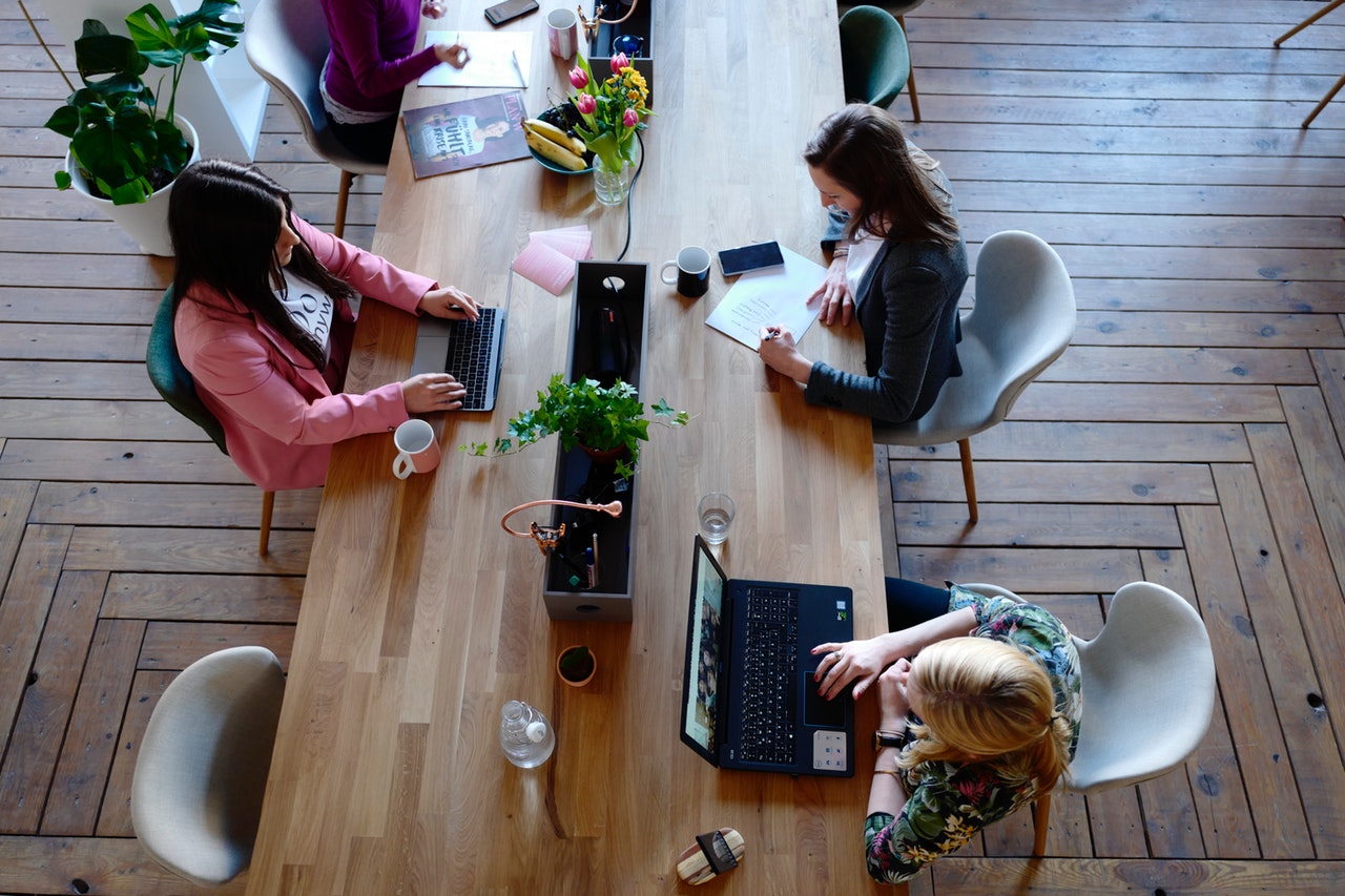 Three woman sitting on white chair in front of table 2041627