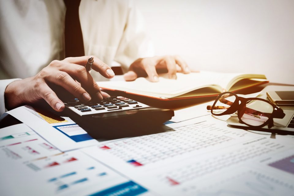 finance concept, business man analyze graph chart with using calculator and computer laptop for profit forecast in the future.